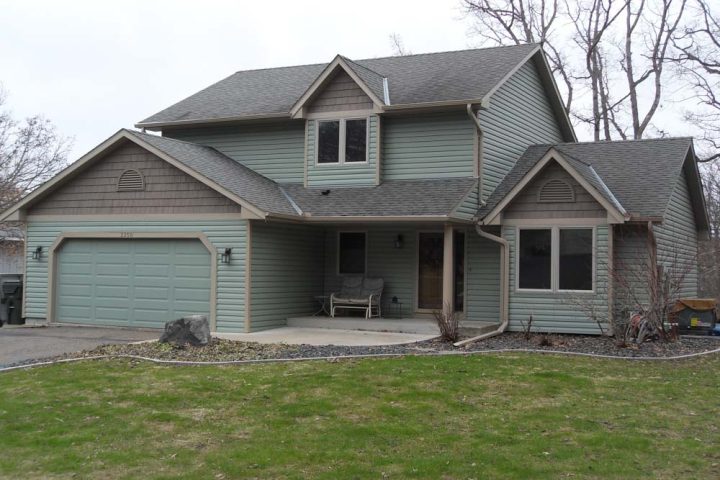 Front view of a house with concrete driveway and front porch, and a grass lawn